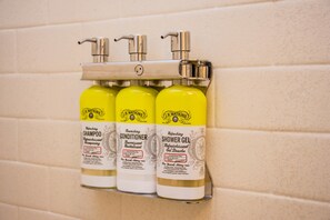 A wall-mounted dispenser with three bottles of J.R. Watkins products: shampoo, conditioner, and shower gel. - Candlewood Suites : Overland Park - W 135th St by IHG (Overland Park)