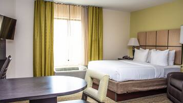 A hotel room with a bed, a desk, a chair, a television, and a window with curtains.