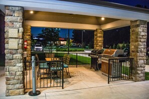 An outdoor patio with a grill, seating, and a stone wall. - Candlewood Suites : Overland Park - W 135th St by IHG (Overland Park)
