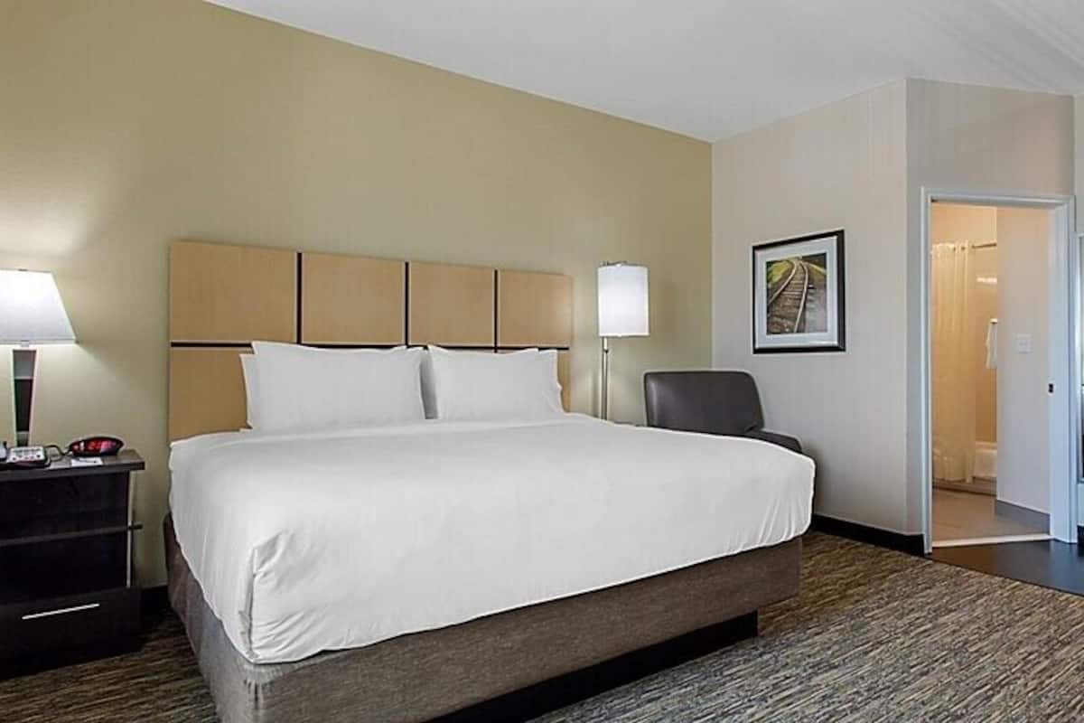 Une chambre d’hôtel avec un grand lit, des tables de chevet, une chaise et un bureau.