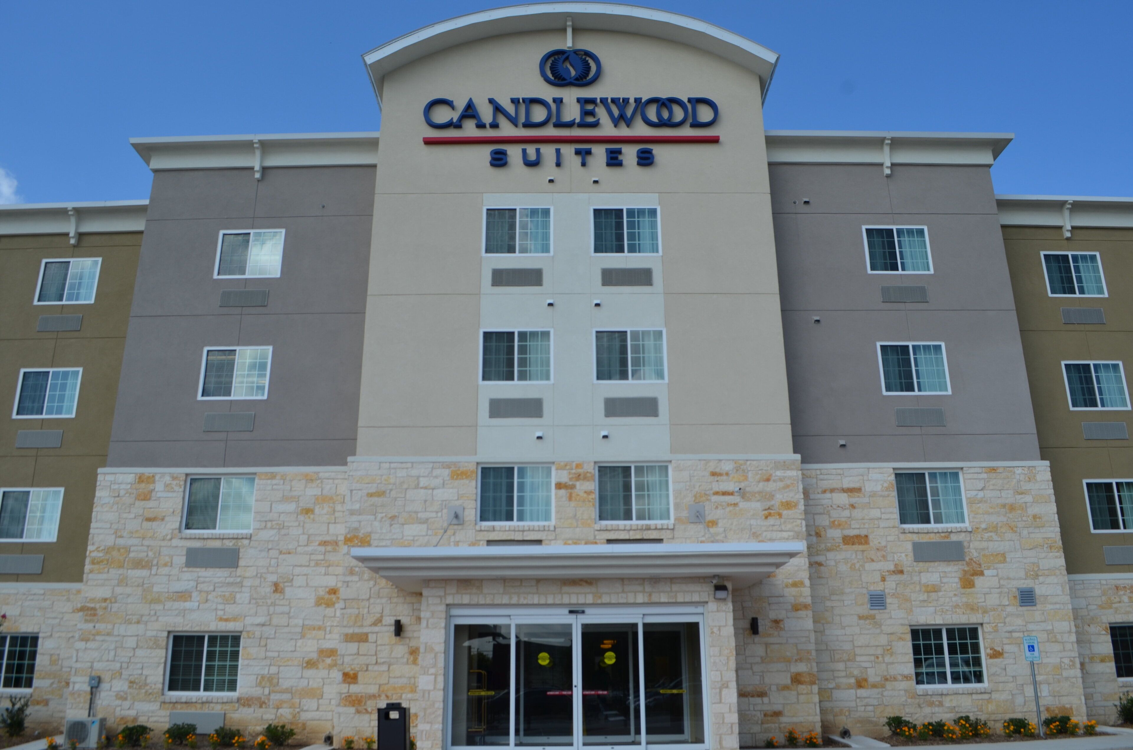 Een meerhoog hotel met een gevel van steen en een bord waarop 'CANDLEWOOD SUITES' staat.