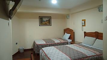 Habitación de hotel con dos camas, un cuadro en la pared, un teléfono y un cesto de basura.