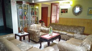 A living room with floral patterned sofas, a coffee table, and a glass cabinet with bottles. - Hotel Panamericano (Lima)