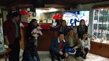 Un grupo de personas en una sala con una mesa de recepción, un televisor y una vitrina de vidrio con objetos.