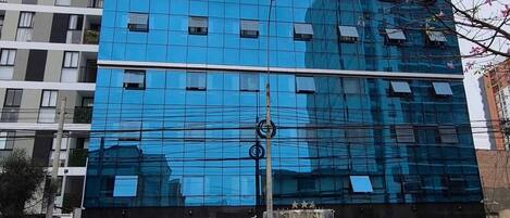 Un moderno edificio de hotel con fachada de vidrio reflectante, un letrero destacado que dice 'HOTEL PANAMERICANO' y una entrada visible.
