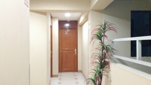 A hallway with a tiled floor, a wooden door at the end, and a potted plant on the right. - Hotel Panamericano (Lima)