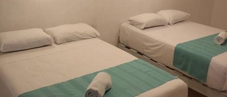 Two single beds with white linens, green bedspreads, and round wall sconces.