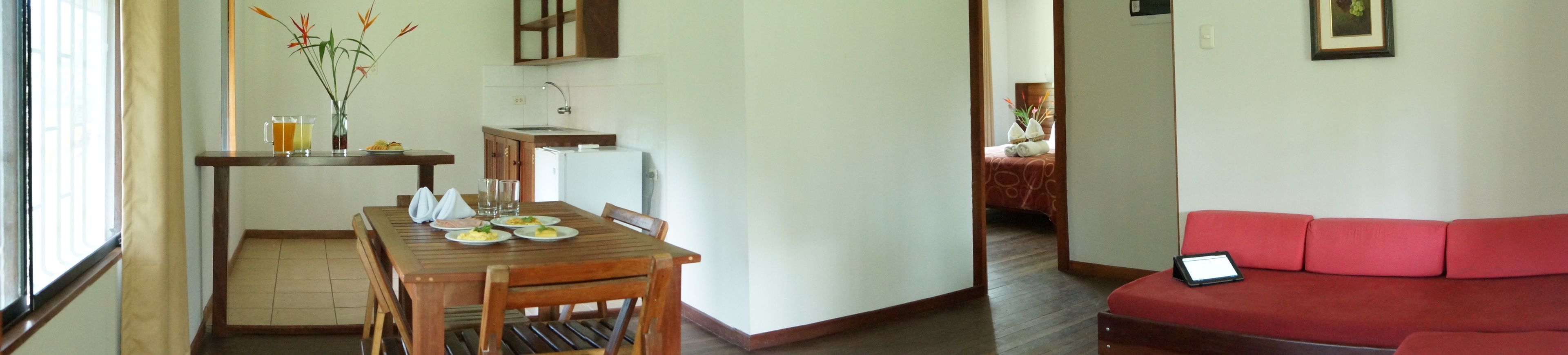 Un espacio habitable compacto con comedor, kitchenette y sofá rojo.