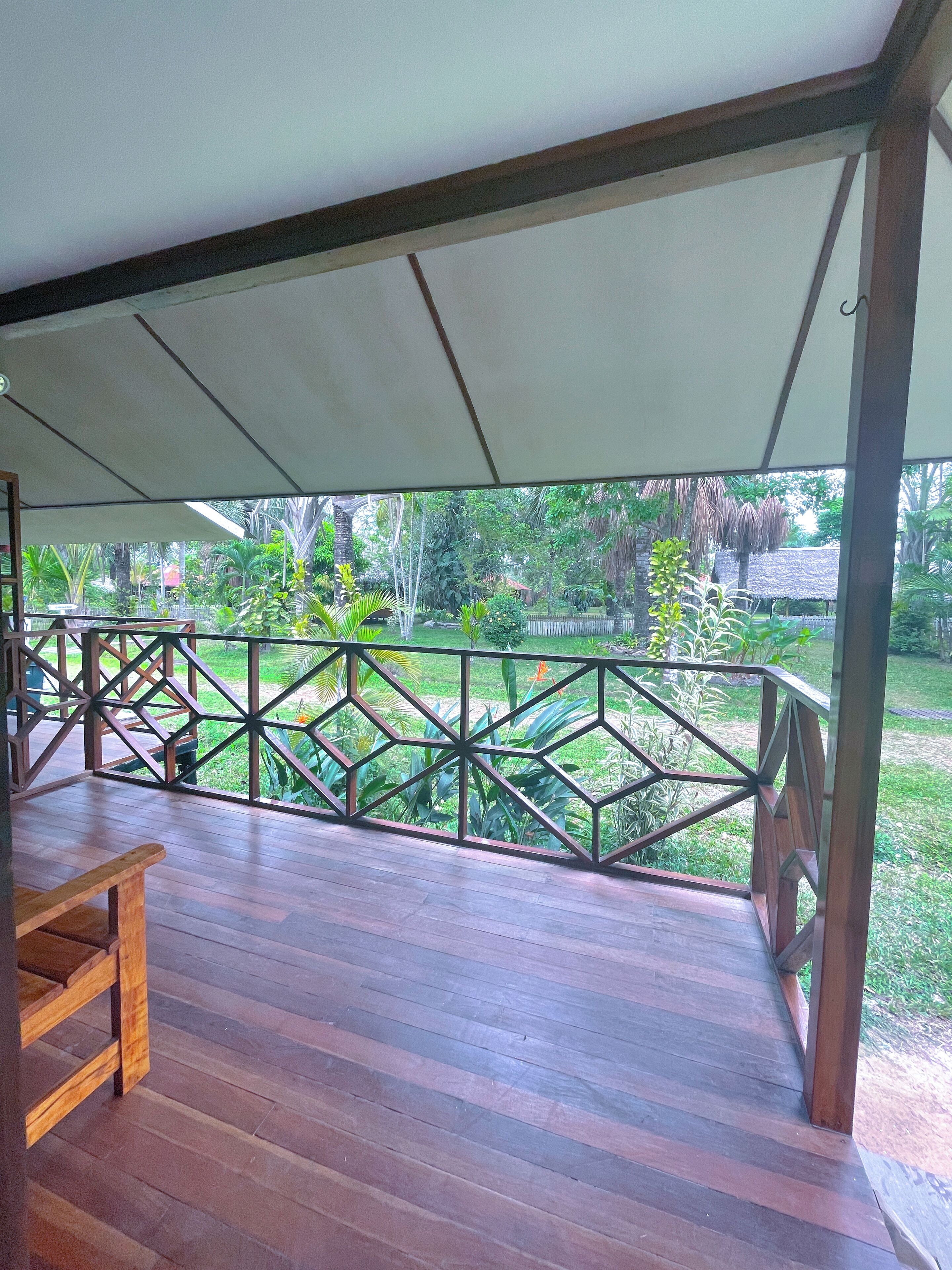 An outdoor wooden deck with a geometric railing and a canopy overhead.