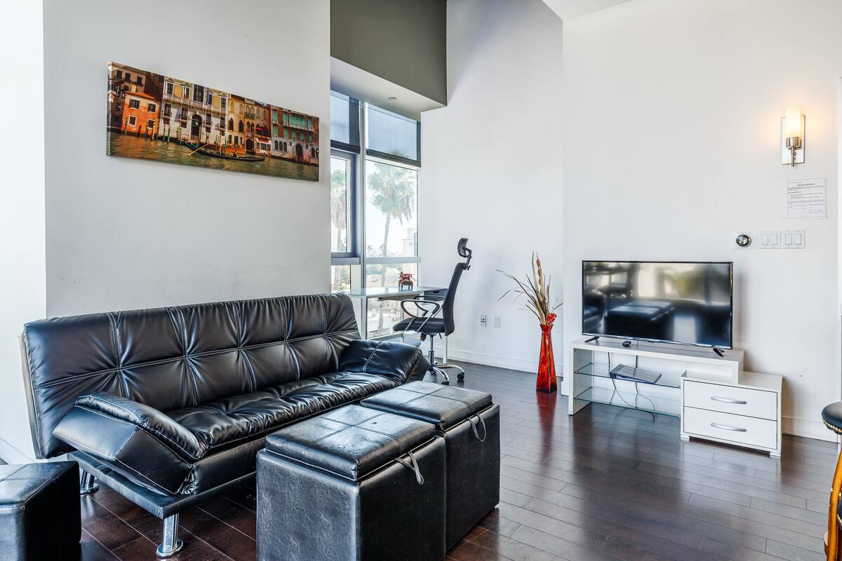 A modern living room with a leather sofa, a TV, and a large window.