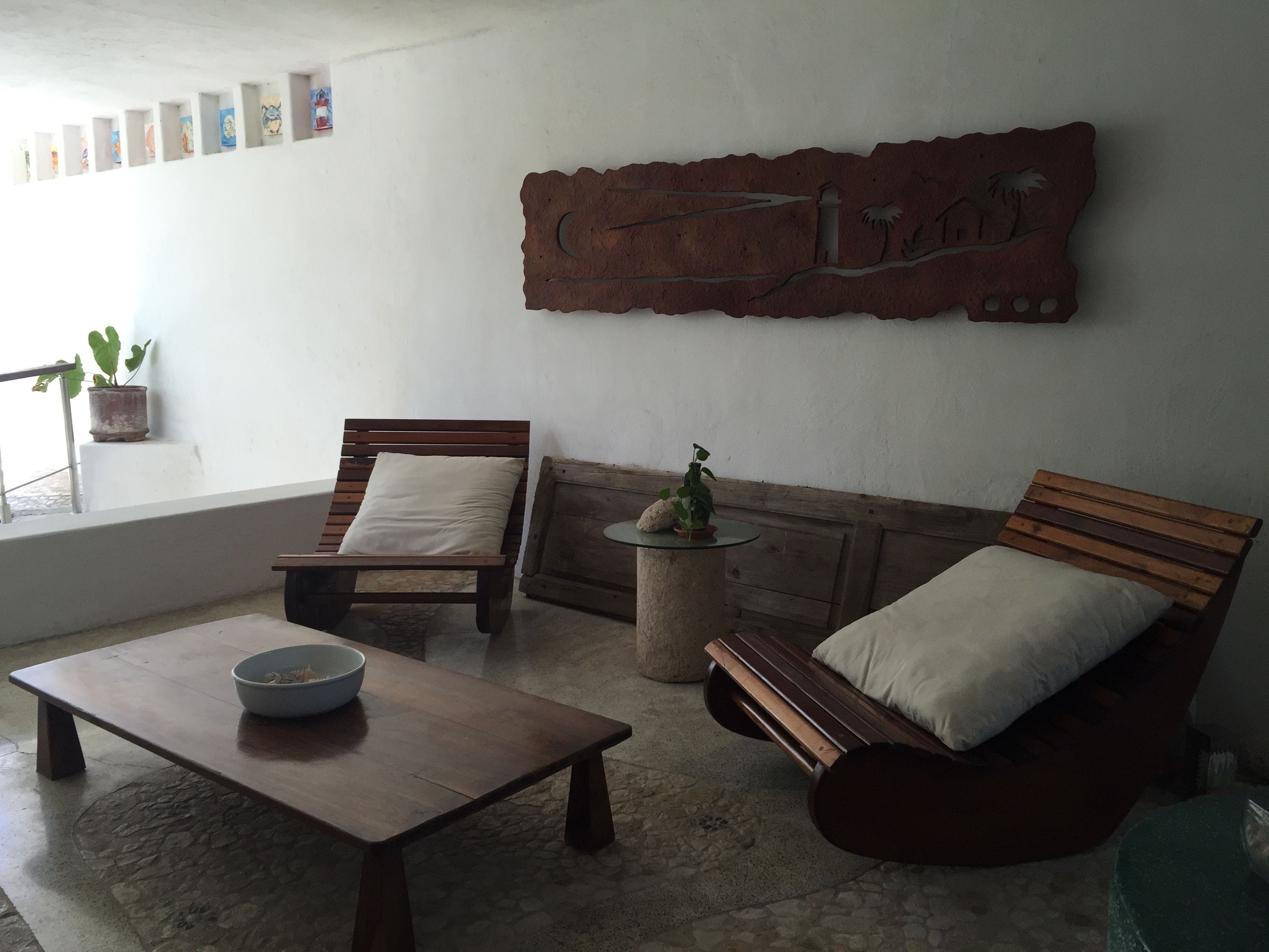 A cozy living area with a wooden bench, a small table with a bowl, and a wall-mounted artwork.