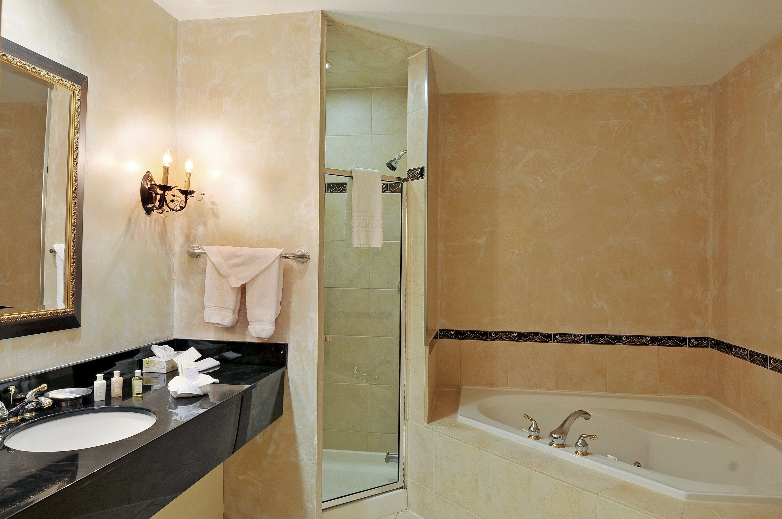 A bathroom with a large mirror, two sinks, a bathtub, and a glass-enclosed shower.