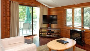 A cozy living room with a sofa, a coffee table, a flat-screen TV, and a wood-burning stove.