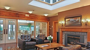 A spacious lobby with leather sofas, a wooden coffee table, and a fireplace.