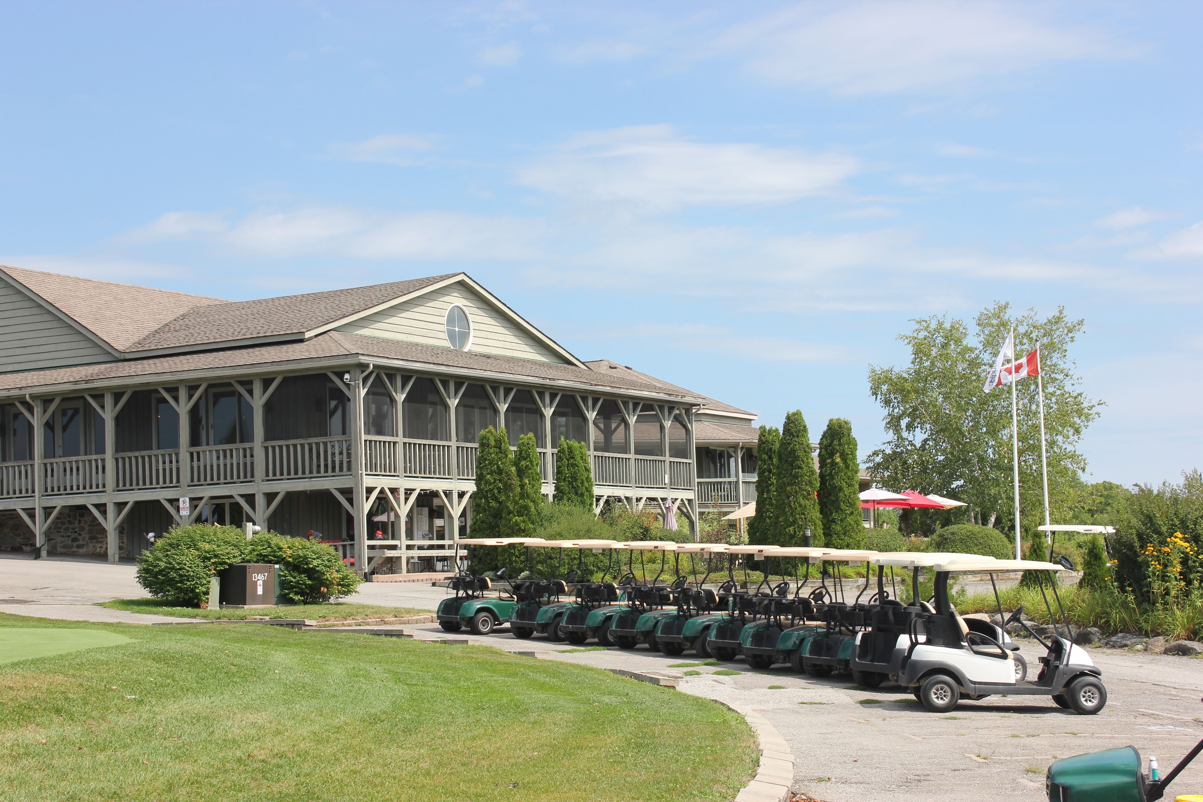 A building with a porch and a row of golf carts parked in front.