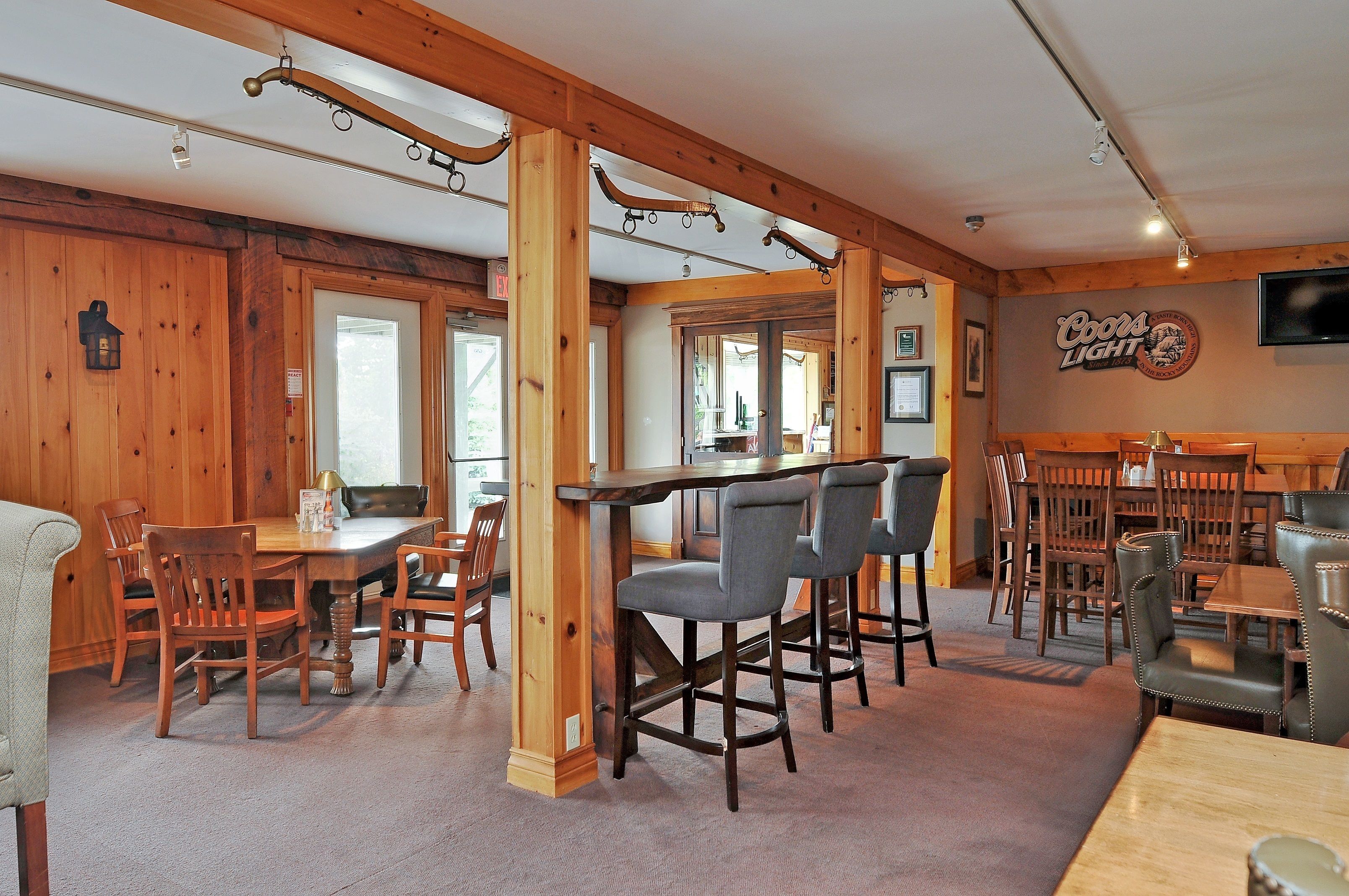 A wooden interior with a bar area, dining tables, and chairs.