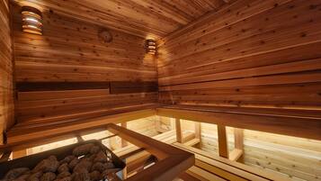 Un sauna avec des murs et des bancs en bois, un banc agrémenté de pierres et un luminaire fixé au mur.