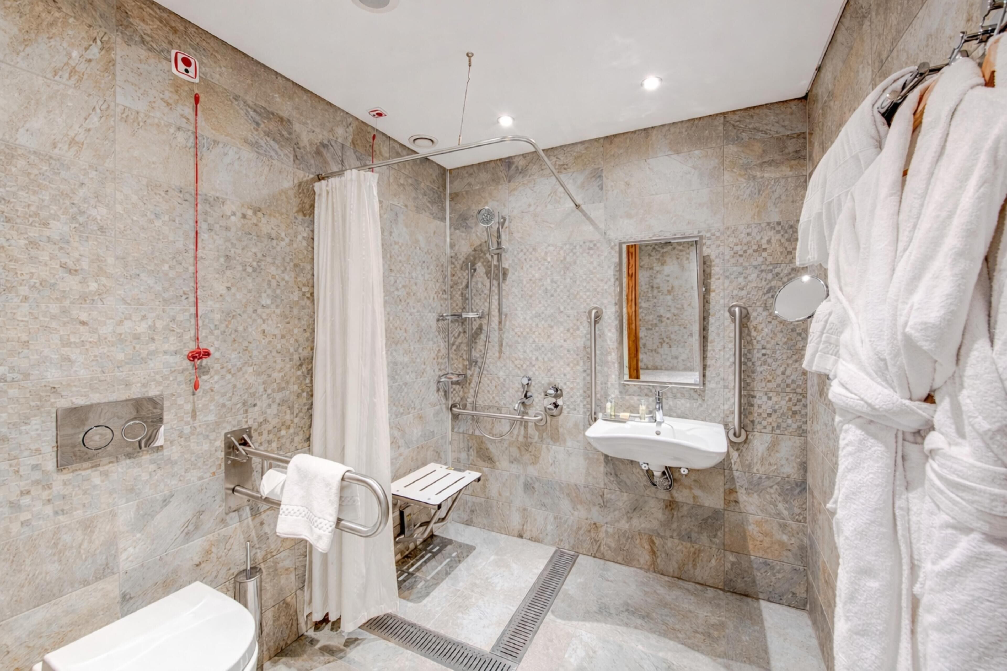 A modern bathroom with a shower, sink, and towel rack.
