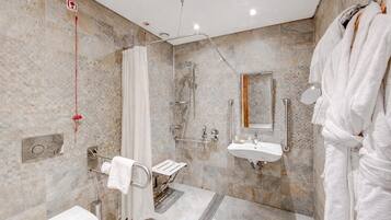 A modern bathroom with a shower, sink, and towel rack.