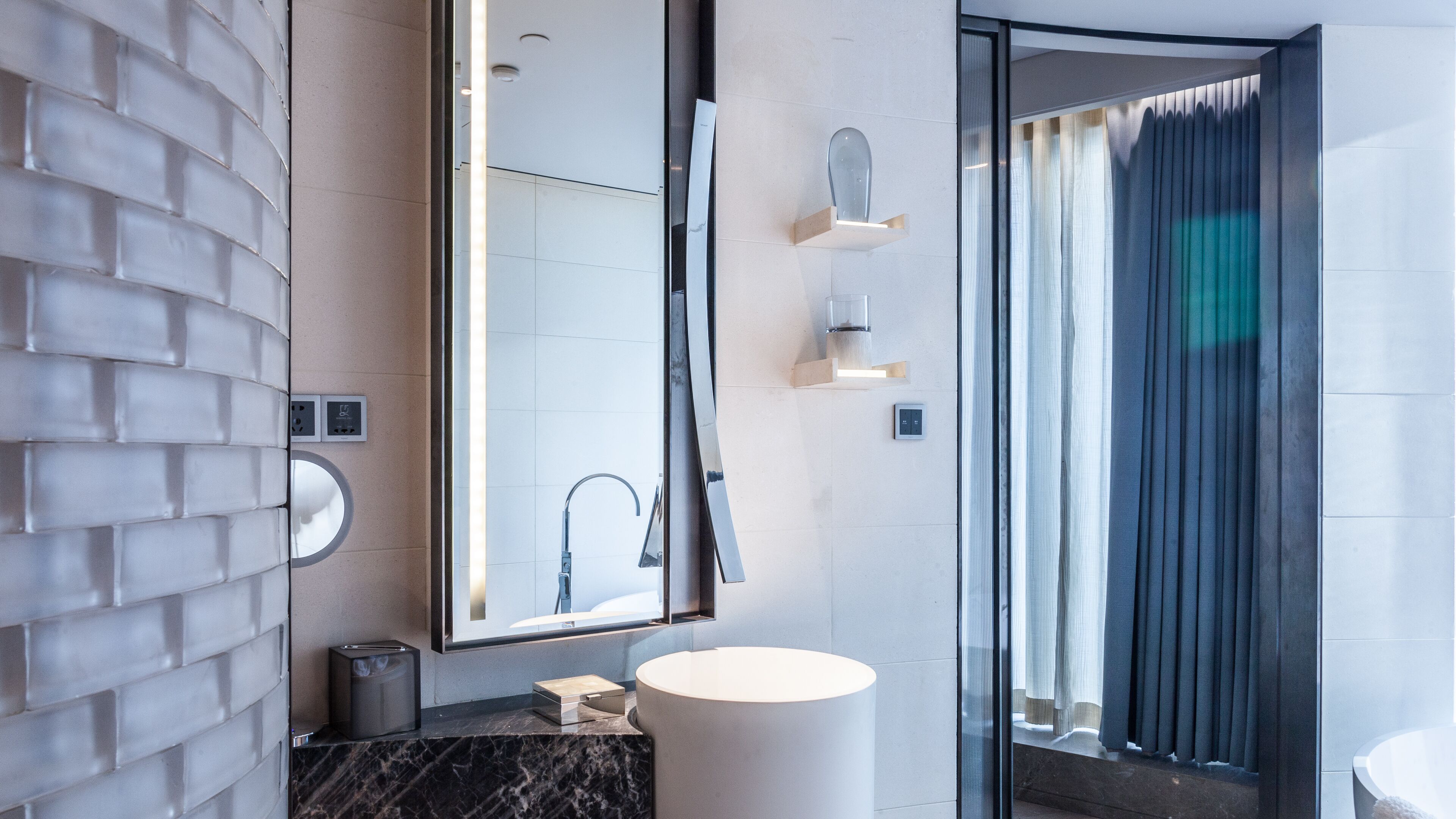A modern bathroom with a marble countertop, a large mirror, and a shower area.