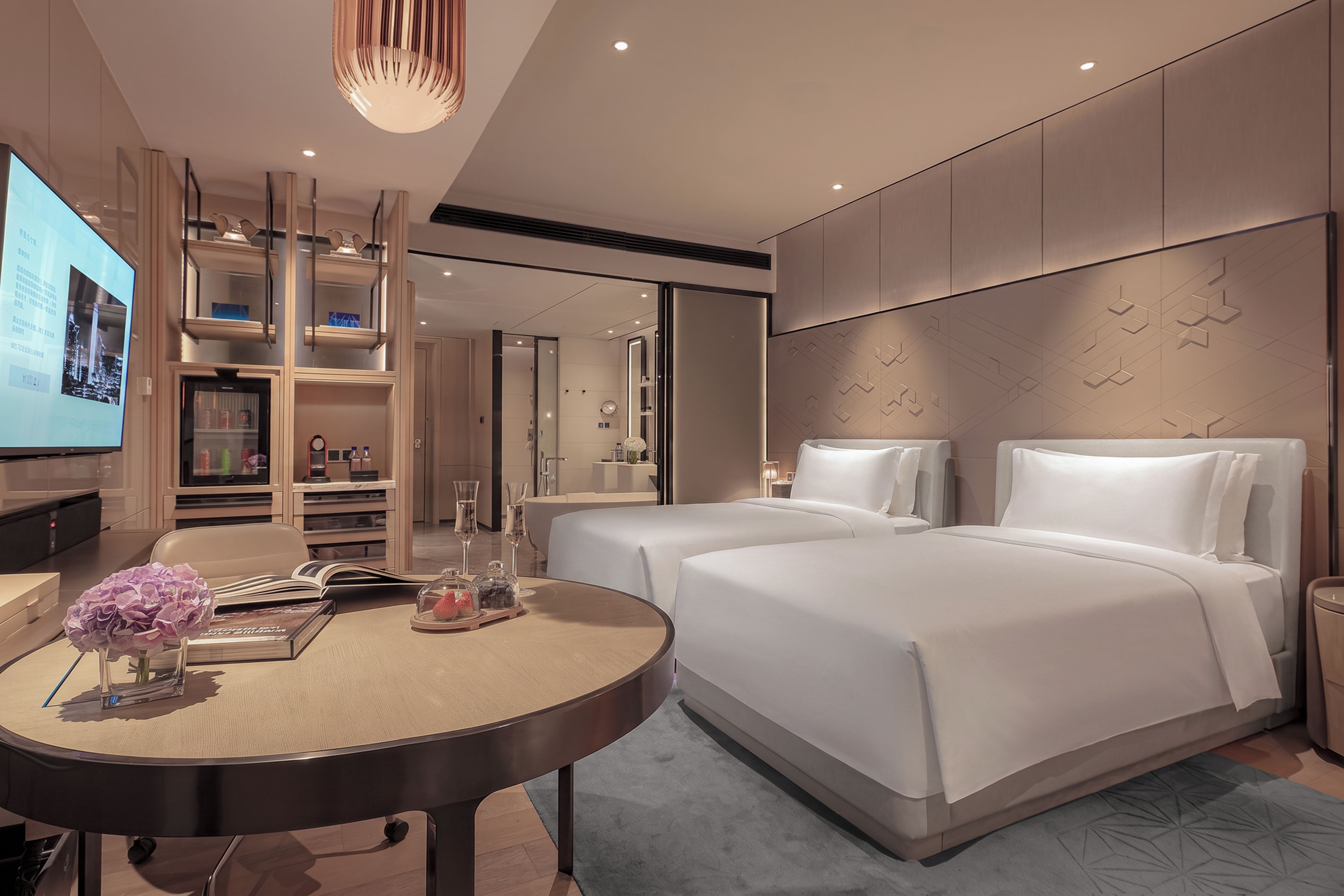 A modern hotel room with a large bed, a desk with a computer, and a TV.