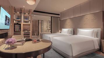 A modern hotel room with a large bed, a desk with a computer, and a TV.