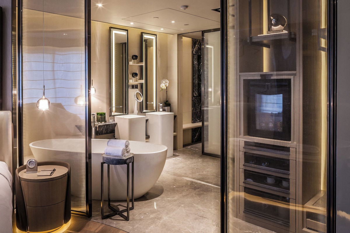 A modern bathroom with a large bathtub, a separate shower area, and a vanity with a mirror.