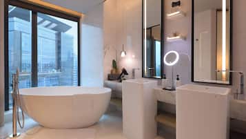 Un baño moderno con una bañera independiente, dos lavamanos y un espejo grande con iluminación integrada.