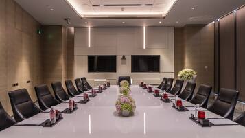 Ein Konferenzraum mit einem langen Tisch, schwarzen Ledersesseln und einer floralen Tischdekoration.
