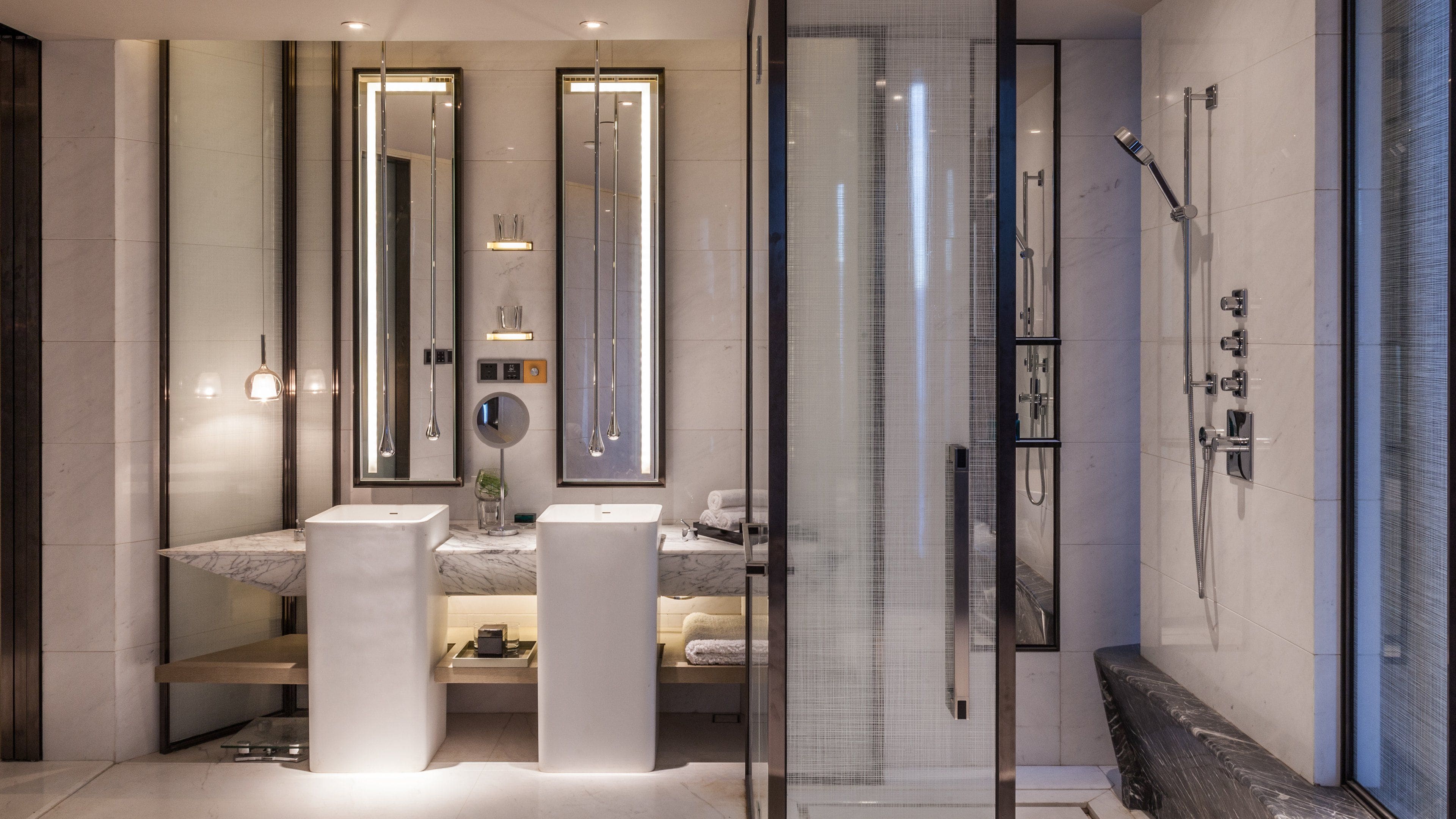 Un bagno moderno con due lavabi, una doccia e cabina doccia in vetro.