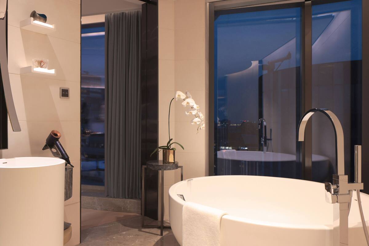 A modern bathroom with two sinks, a large bathtub, and a mirror.