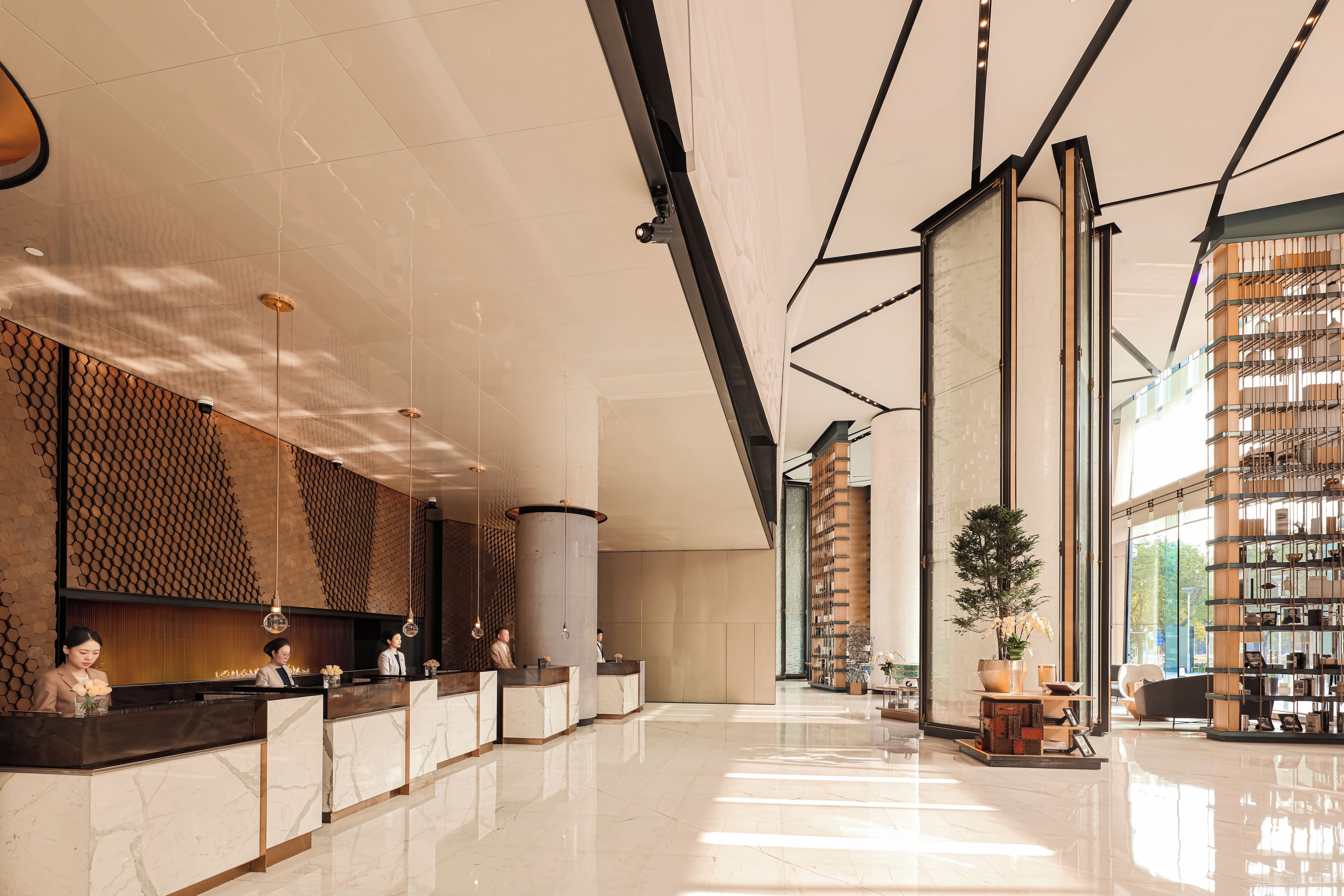 A hotel lobby with a reception desk, a large column, and a plant.