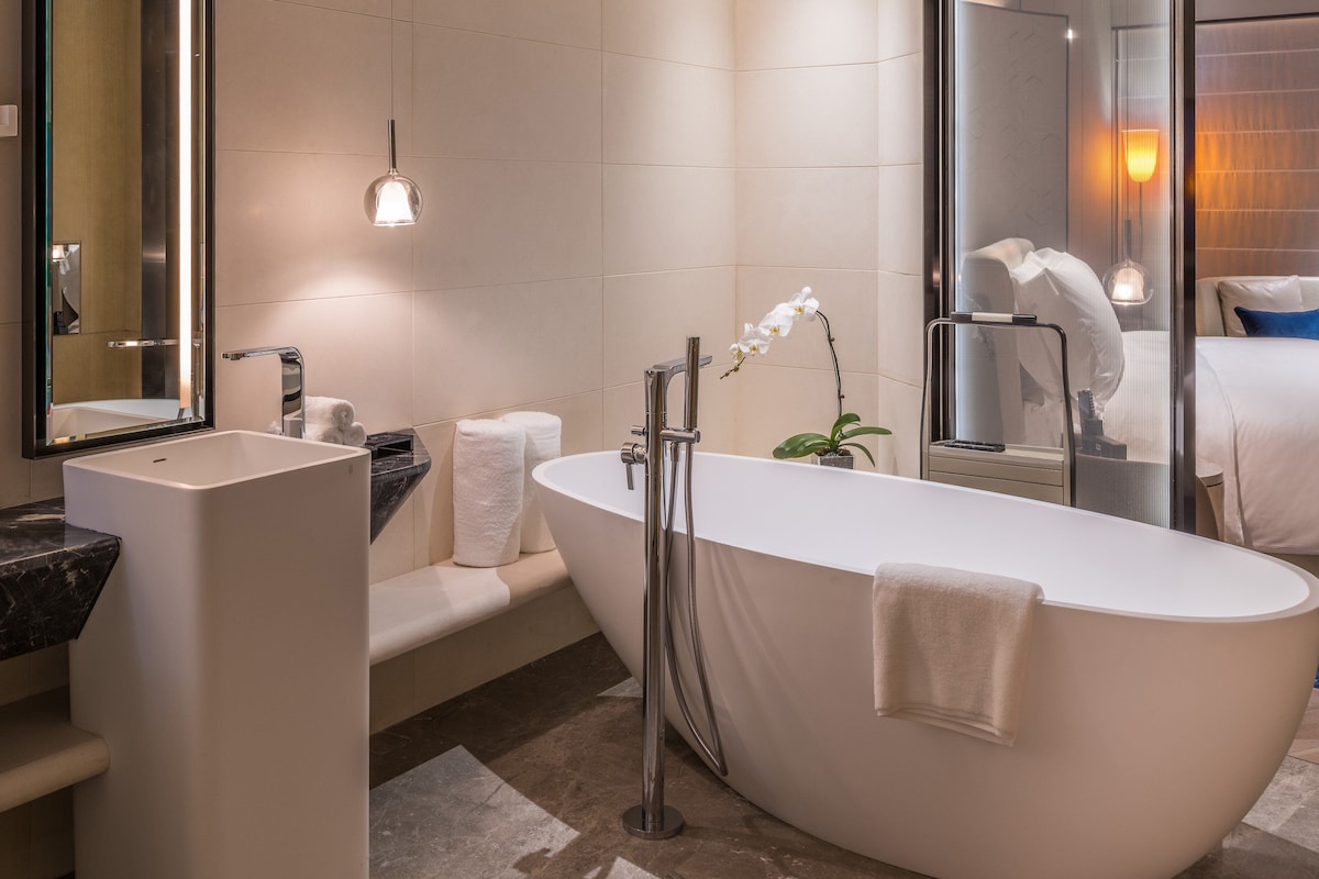 A modern bathroom with a freestanding bathtub, a large mirror, and a shower area.