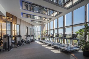 A modern gym with multiple treadmills, weight machines, and large windows offering city views. - InterContinental Beijing Sanlitun by IHG (Beijing)
