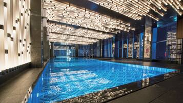 Une piscine intérieure moderne, dotée d’un carrelage aux motifs géométriques, et entourée d’un décor intérieur élégant et contemporain.