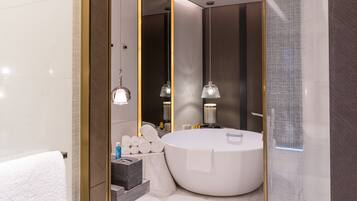 Un baño moderno con una bañera grande, un espejo redondo y dos lámparas colgantes.