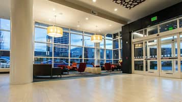 A spacious lobby with large windows, a seating area with chairs, and an exit sign.