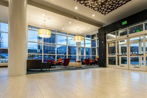 A spacious lobby with large windows, a seating area with chairs, and an exit sign. - Holiday Inn & Suites Chattanooga Downtown by IHG (Chattanooga)
