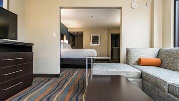 A hotel room with a bed, a sofa, a TV, and a desk.
