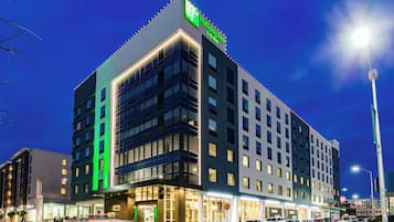 A multi-story hotel with a prominent sign at the top, large windows, and a well-lit entrance.