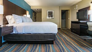 A hotel room with a bed, a desk, a television, and a door leading to a bathroom. - Holiday Inn & Suites Chattanooga Downtown by IHG (Chattanooga)