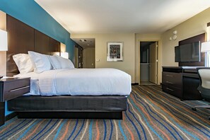 A hotel room with a bed, a desk, a chair, a television, and a carpeted floor. - Holiday Inn & Suites Chattanooga Downtown by IHG (Chattanooga)