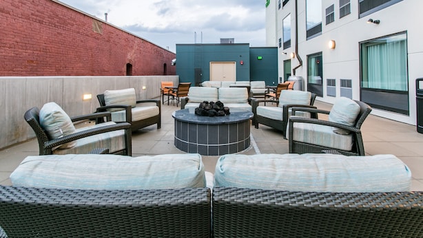 A rooftop patio with wicker furniture, a circular seating area, and a brick wall. - Holiday Inn & Suites Chattanooga Downtown by IHG (Chattanooga)
