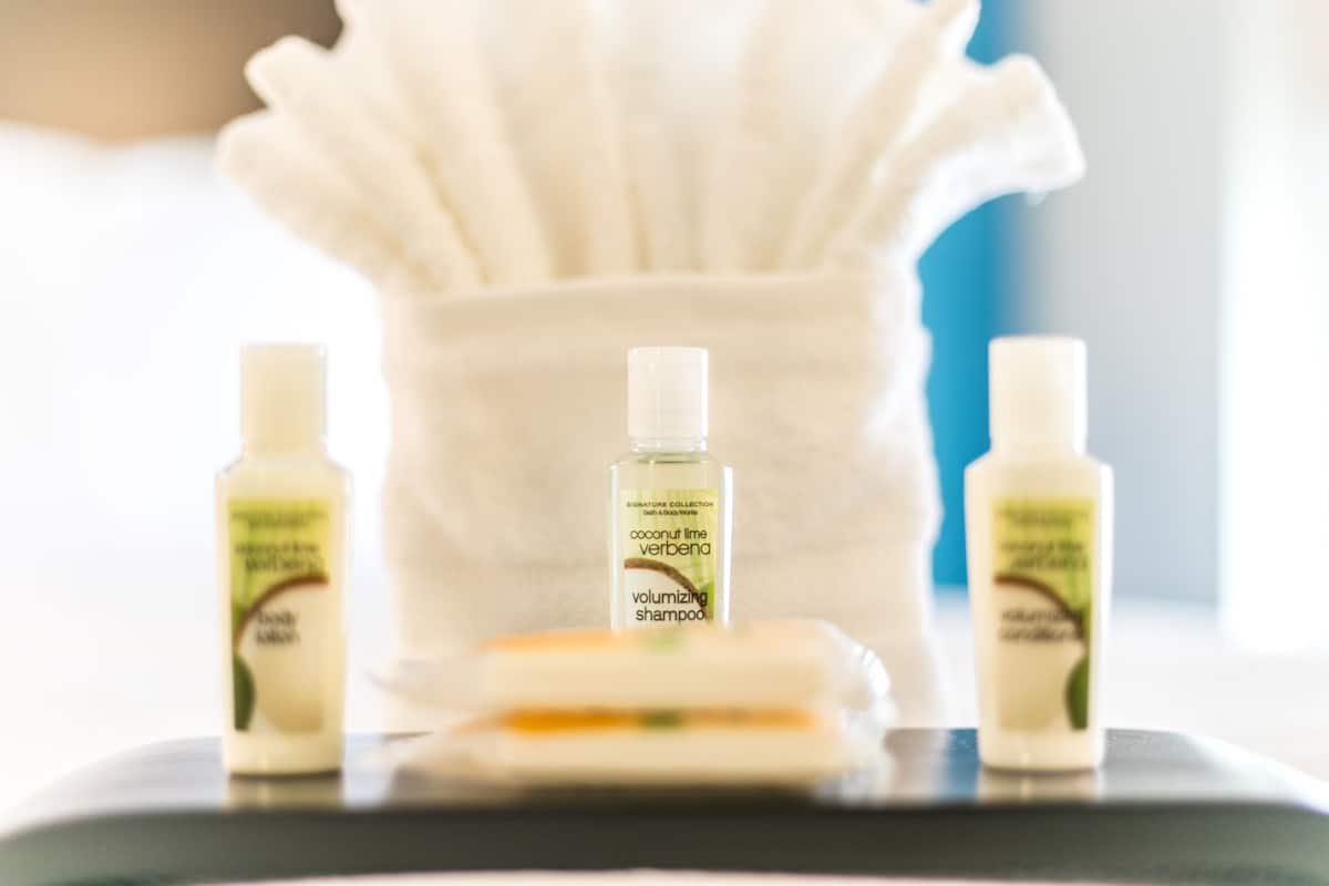 Un meuble-lavabo de salle de bain avec trois bouteilles de shampoing au parfum de noix de coco, citron vert et verveine, et un savon.