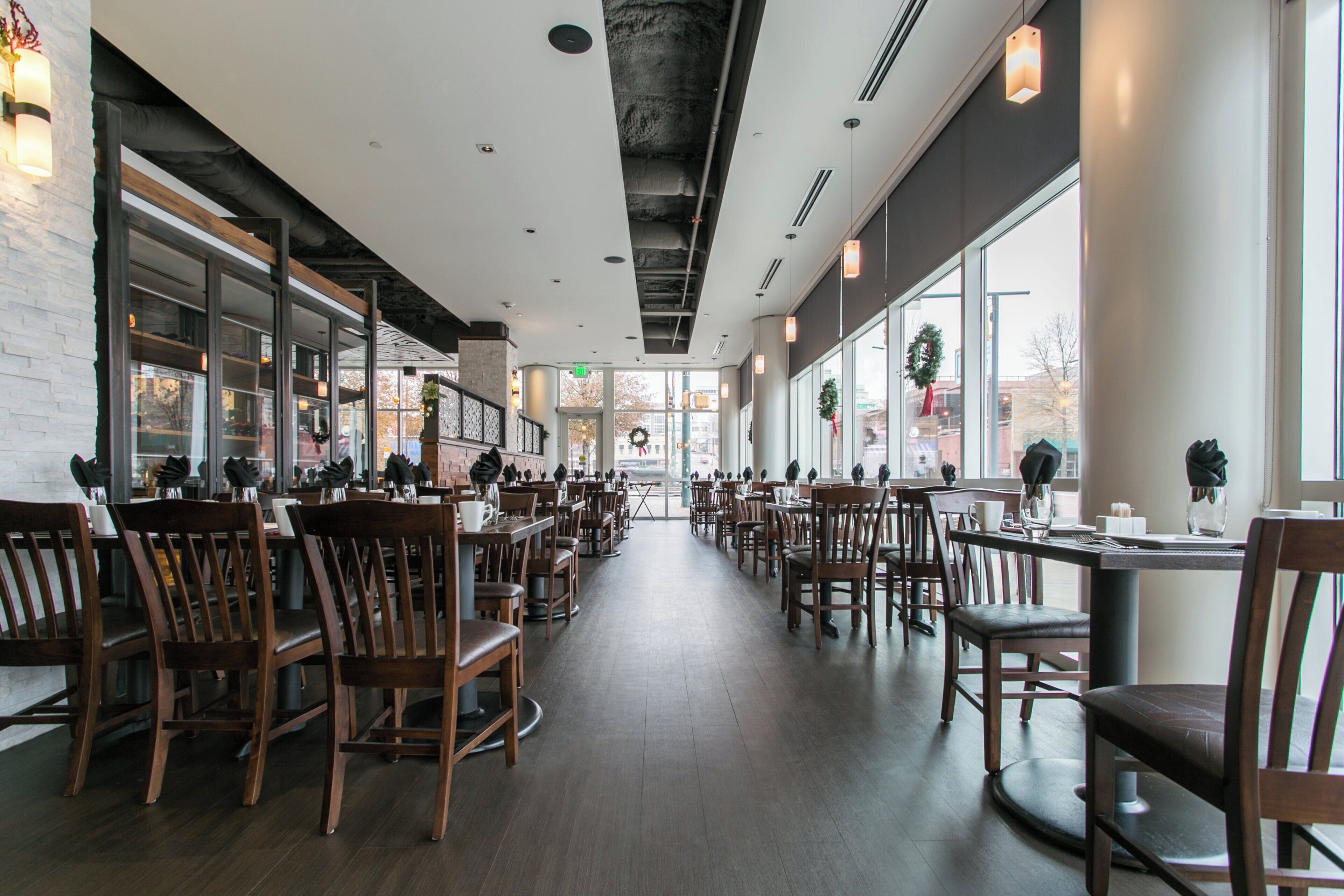 A spacious restaurant with high ceilings, large windows, and a modern interior design.