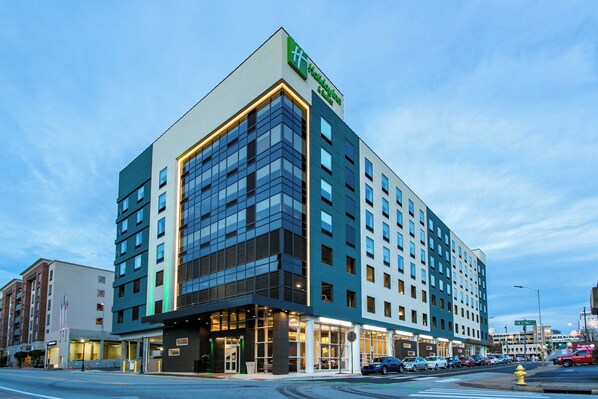 A modern hotel with a prominent glass facade, multiple floors, and a flat roof.