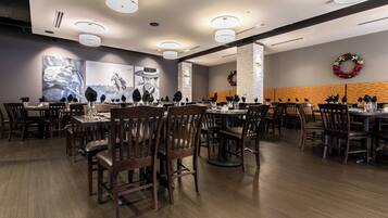 Un comedor con varias mesas y sillas, luces de techo y adornos en la pared.