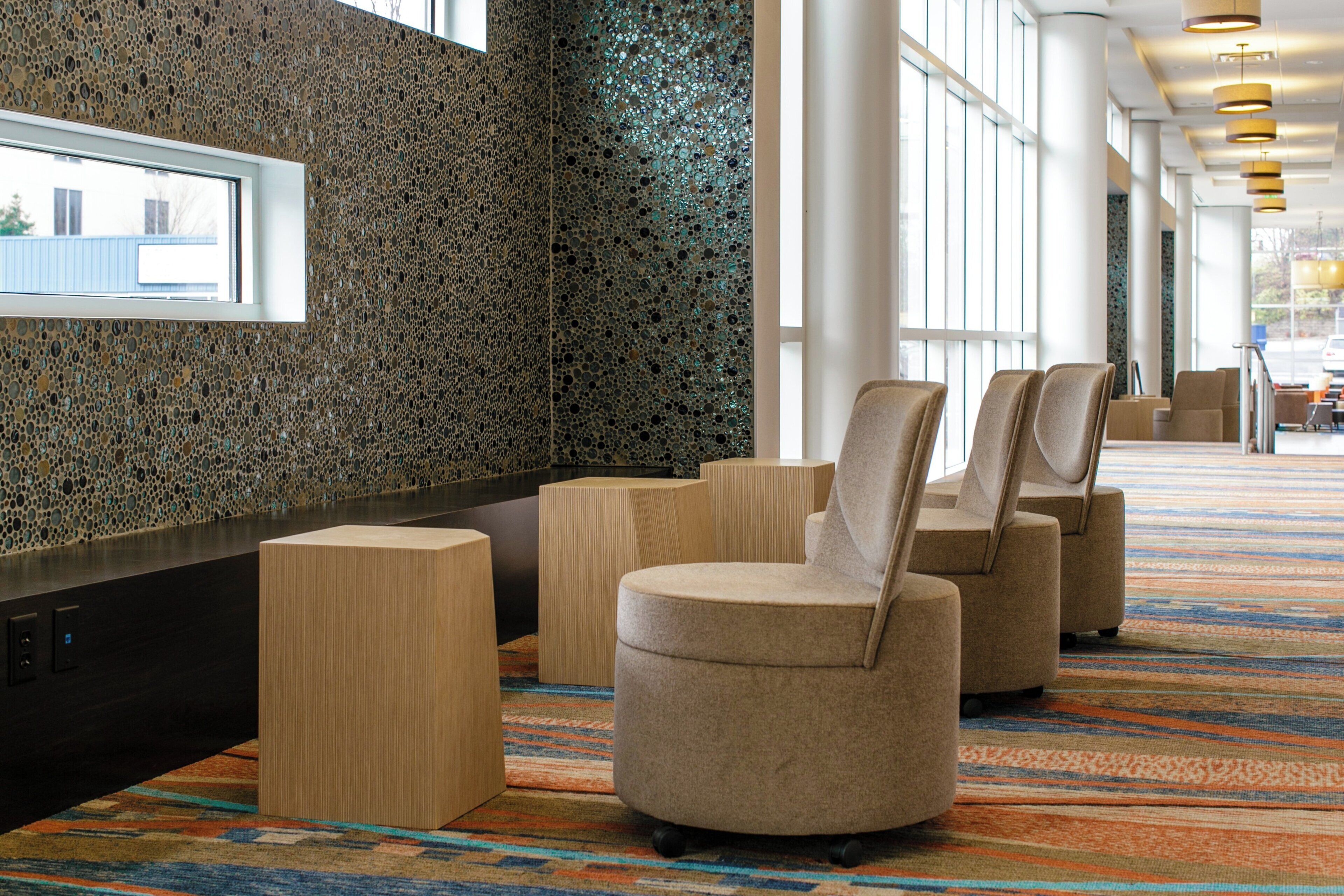 A modern lobby with a patterned wall, seating area, and a view of the outdoors.