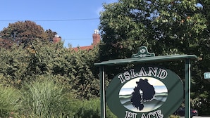 Une enseigne indiquant « Island Place », avec une affiche « Complet », le tout entouré de fleurs colorées et de verdure.