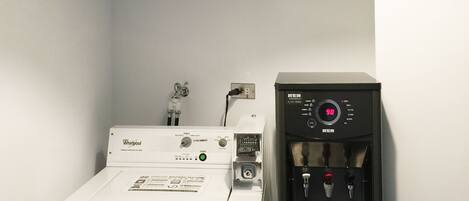 A compact laundry room with a Whirlpool washer and a water dispenser.